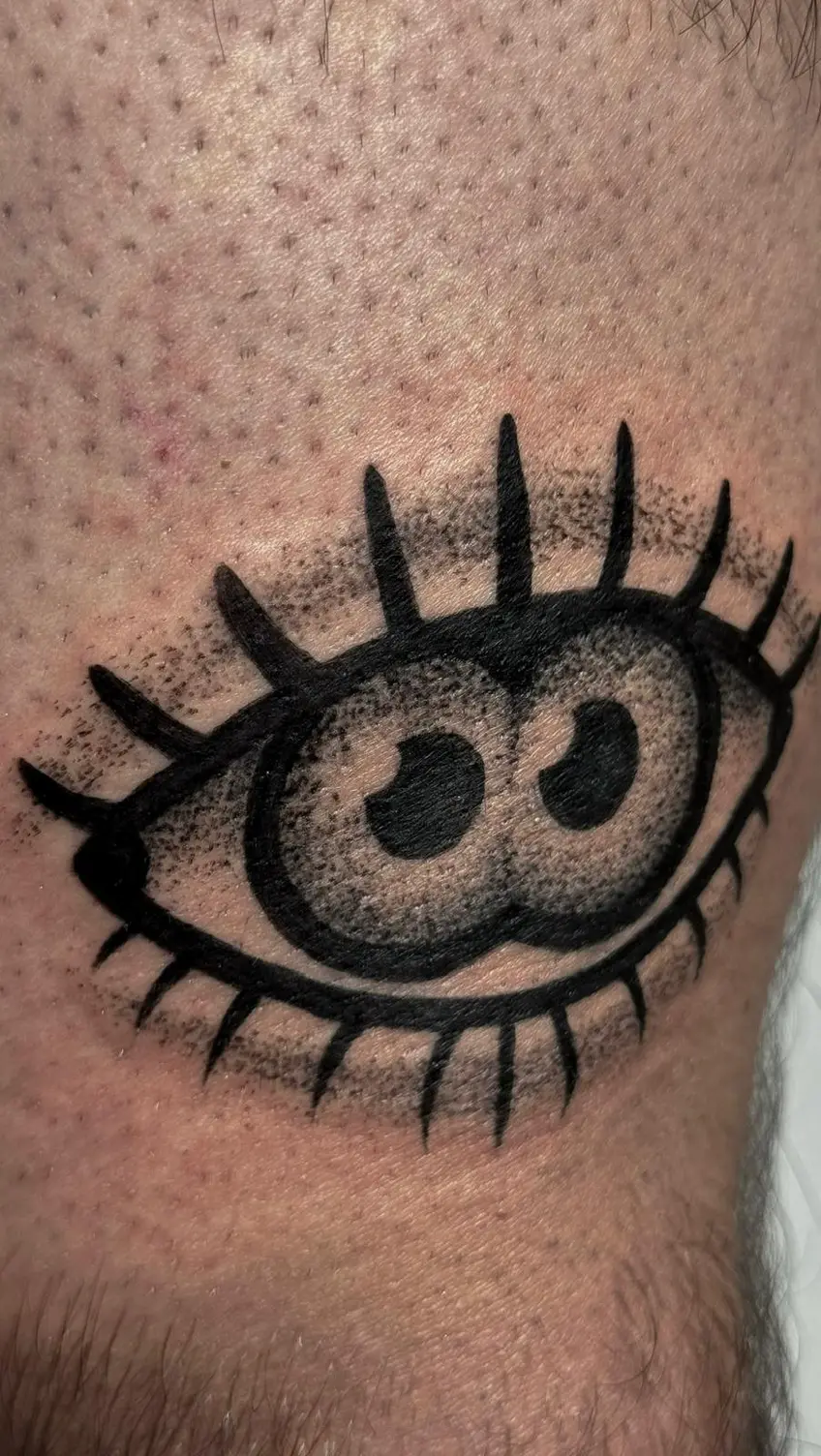 Tatuaje blackwork de un ojo con pestañas radiales y relleno en puntillismo