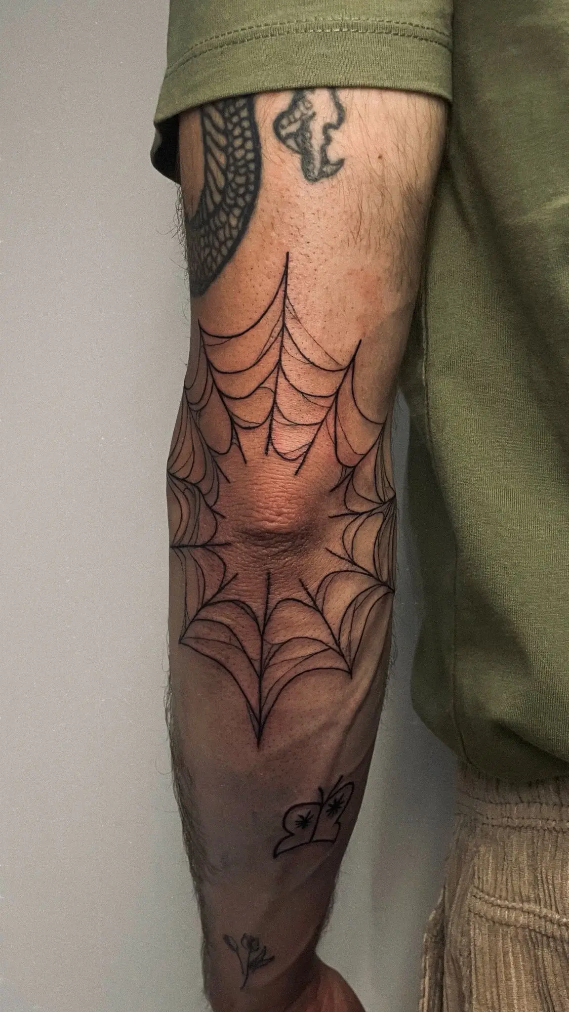 Detalle del tatuaje de telaraña sobre el codo